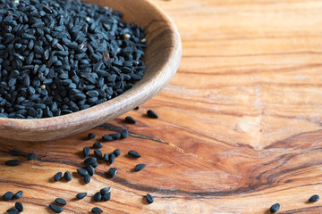 Black cumin seeds on a wooden spoon with copy space