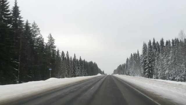 Vehicle driving on snowy slippery highway, first person view from front windglass with empty road