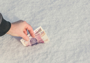A man's hand reaches for Polish zloty in the snow. Frozen Accounts. Bankruptcy. Concept