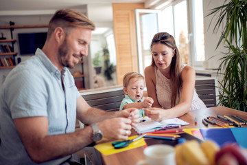 Smiling family drawing together in kitchen at home