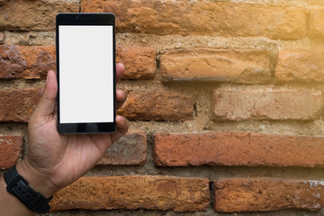 Hand holding smartphone with blank screen, isolated on brown brick wall background.