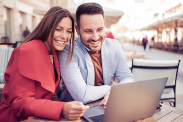 Couple talking and using laptop at cafe