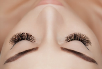 Eyelash extension procedure close up. Beautiful Woman with long lashes in a beauty salon.
