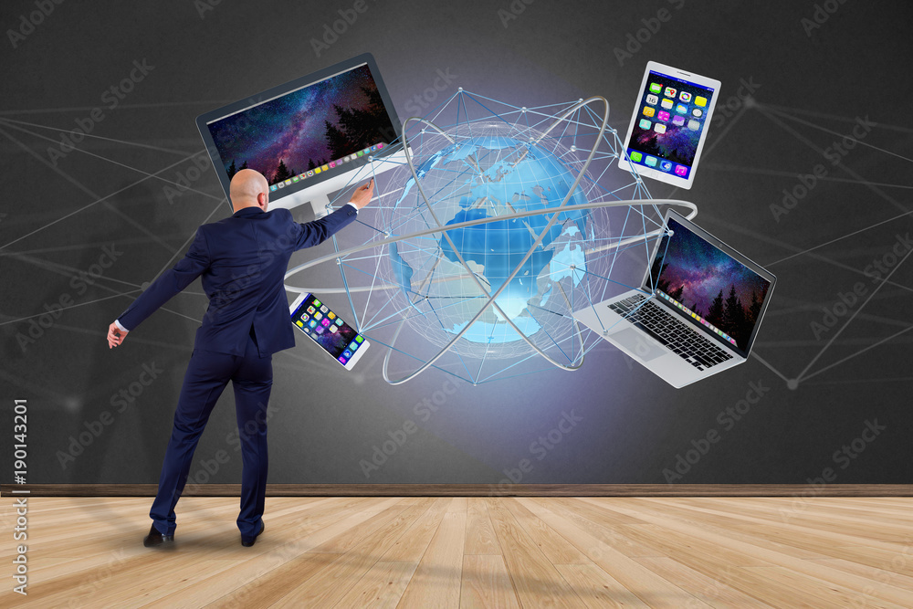 Poster businessman in front of a wall with a computer and devices displayed on a futuristic interface with 