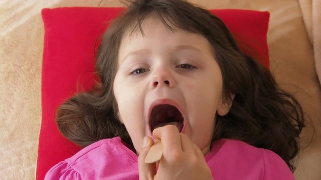 The throat of a child. A sick little girl looks at her throat.