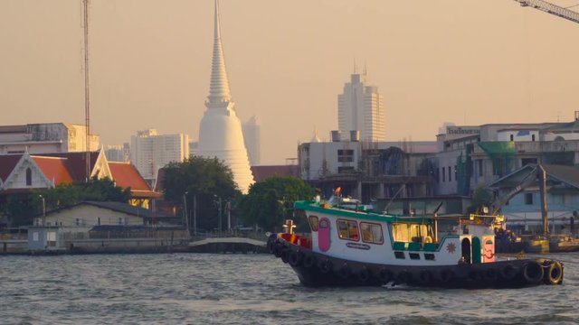 Small boat sails along the Chao Phraya river in Bangkok