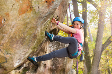 Teenage girl in helmet climbing on the rock route
