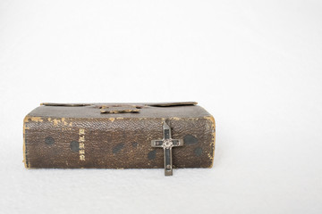Antique Worn Leather Bible with Antique Cross of Metal and Wood on White Background