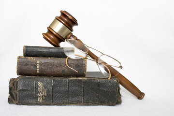 Stack of Antique Worn Leather Bibles with Gavel and Glasses on White Background