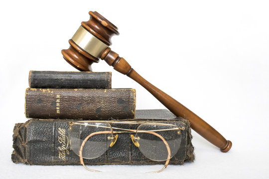 Three Antique Worn Leather Bibles with Gavel and Antique Glasses on White Background