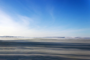 The frozen river, leaving in the distance, in sunny weather under the blue sky