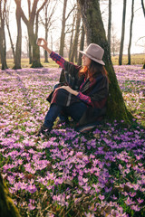 Spring crocuses in forest and a female traveler