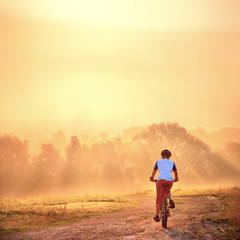 Young man on bicycle in sunrise light