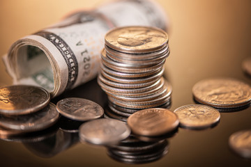 close up detail rolled up us dollar bills and coins on wood background 