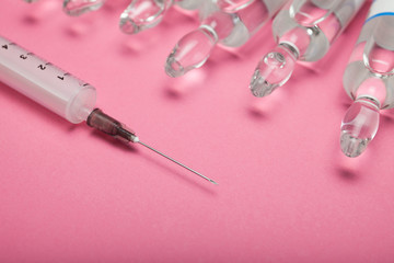 Syringe and ampoules on a pink background. Injections for face and skin rejuvenation.