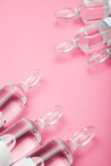 Cosmetic injection of Botox, ampoules with hyaluronic acid and collagen on a pink background.