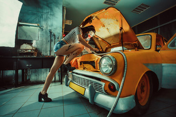 Sexy woman is welding something inside an old car.