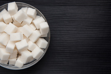 White sugar on black background with copy space