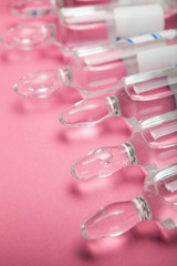 Ampoules with botox, hyaluronic acid and collagen on a pink background, rejuvenating therapy.