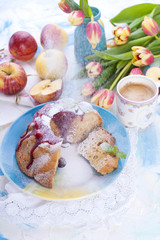 A bouquet of fresh tulips. Sweet home cupcake with sugar. Coffee in a cup. Apples on the table.