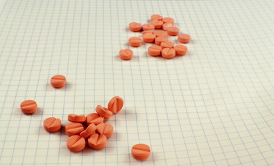 Many pills lie on a white checkered background