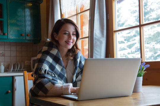 portrait of beautiful redhead girl in plaid sitting at table with computer