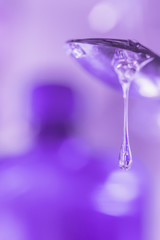 Liquid droplet of medical syrup flows from the spoon close-up.