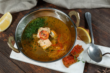 Fresh fish soup with ingredients and spices for cooking. Wooden background