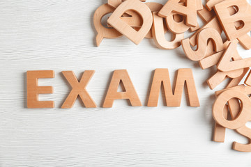 Word EXAM made of letters on wooden background