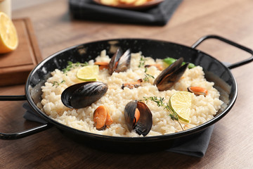 Dish with delicious seafood risotto on wooden table