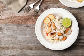 Plate with delicious seafood risotto on wooden table