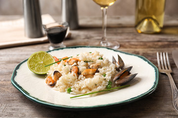 Plate with delicious seafood risotto on wooden table