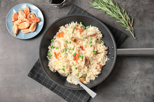 Frying pan with delicious seafood risotto on table