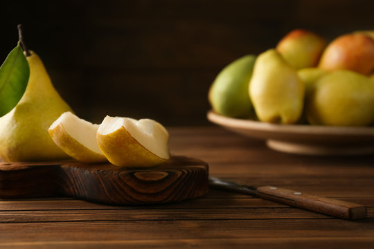Wooden board with cut pear on table