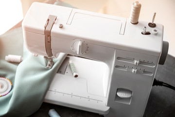 Modern sewing machine with fabric and threads on table