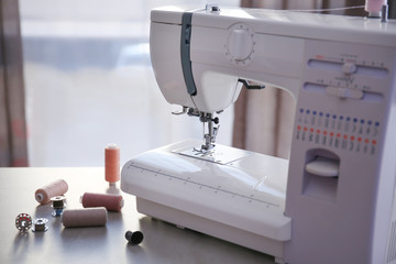 Modern sewing machine with threads on table