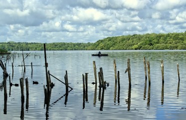 Nature,environment and landscape concept-landscape of a lake,an old port with a fisherman on a boat.