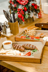 Top view. Grilled beef sausages with chips, mushrooms puree, vegetables, pepper, tomato sauce, ketchup, chilli on wooden background. Christmas concept, gifts, winter menu restaurant