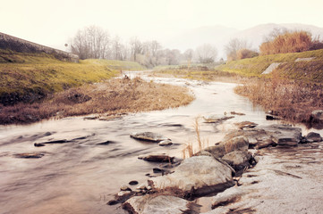 Panoramic view of the Pescia river, in the Italian countryside, with water and stones in the...