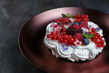 Meringue dessert cake with fresh berries on wood background