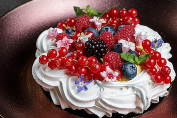 Meringue dessert cake with fresh berries on wood background
