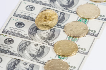 Golden bitcoin coin on us dollars close up.