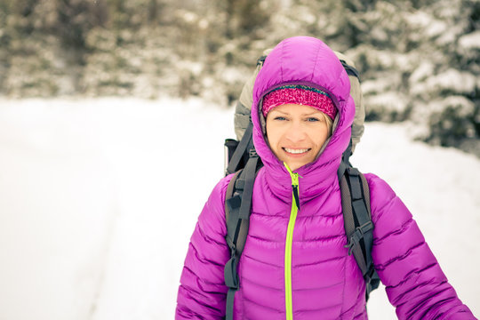 Happy woman walking in winter forest with backpack