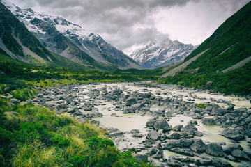 Hooker Valley Track hiking trail, New Zealand. River leading to Hooker lake with glacier over view of Aoraki Mount Cook National Park with snow capped mountains landscape. Summer nature.