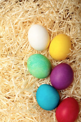 Fototapeta na wymiar Easter egg cyan , white, yellow,red, purple.Colored chicken egg .On hay background.Soft Easter background. Top view.Copy space
