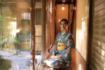 A Japanese woman with kimono in traditional Japanese room, with green trees as background in Spring.