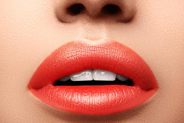 Close-up macro shot of female mouth. Sexy Glamour red lips Makeup with sensuality gesture. Orange colour