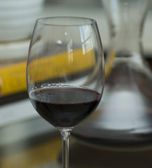 A glass of red wine and the decanter on the table