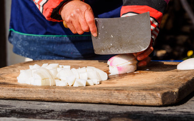 Closeup image of woman hand and Kitchen knife, cutting turnip on kitchen board.