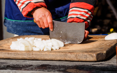 Closeup image of woman hand and Kitchen knife, cutting turnip on kitchen board.